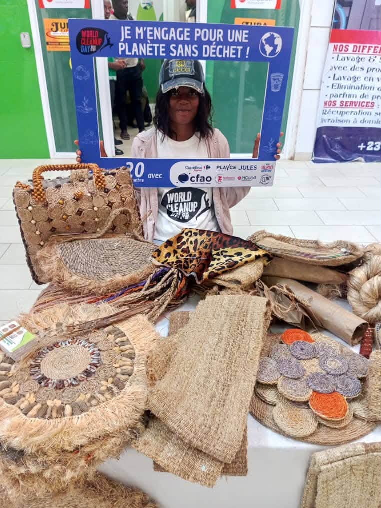 Artisane derrière sa table de créations en fibres, tenant un cadre World Cleanup Day