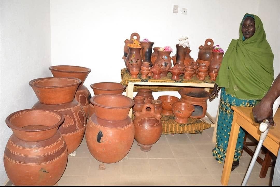 Artisane entourée de jarres, pots et objets en terre cuite