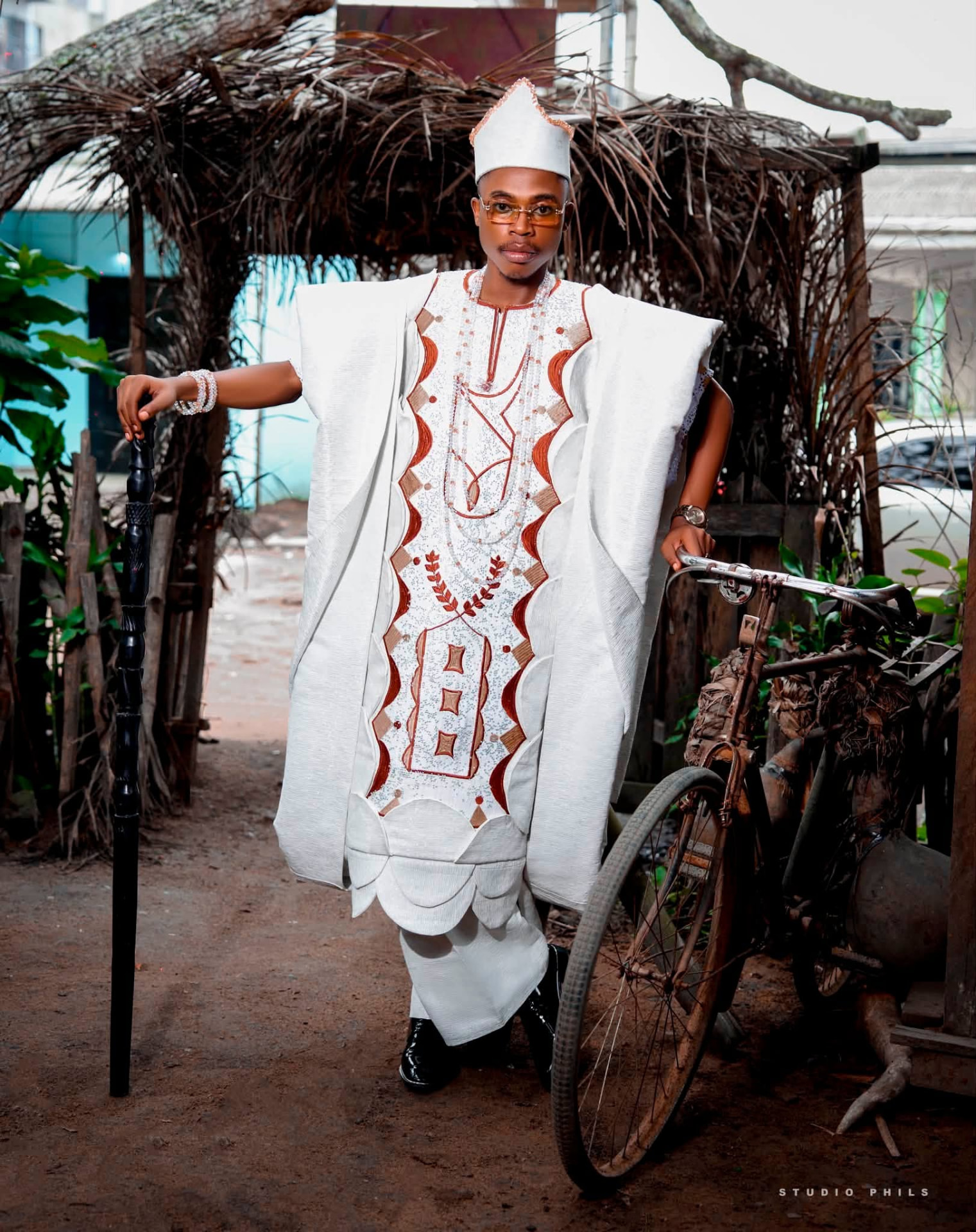 Grand boubou blanc brodé de motifs ocre, porté avec coiffe traditionnelle