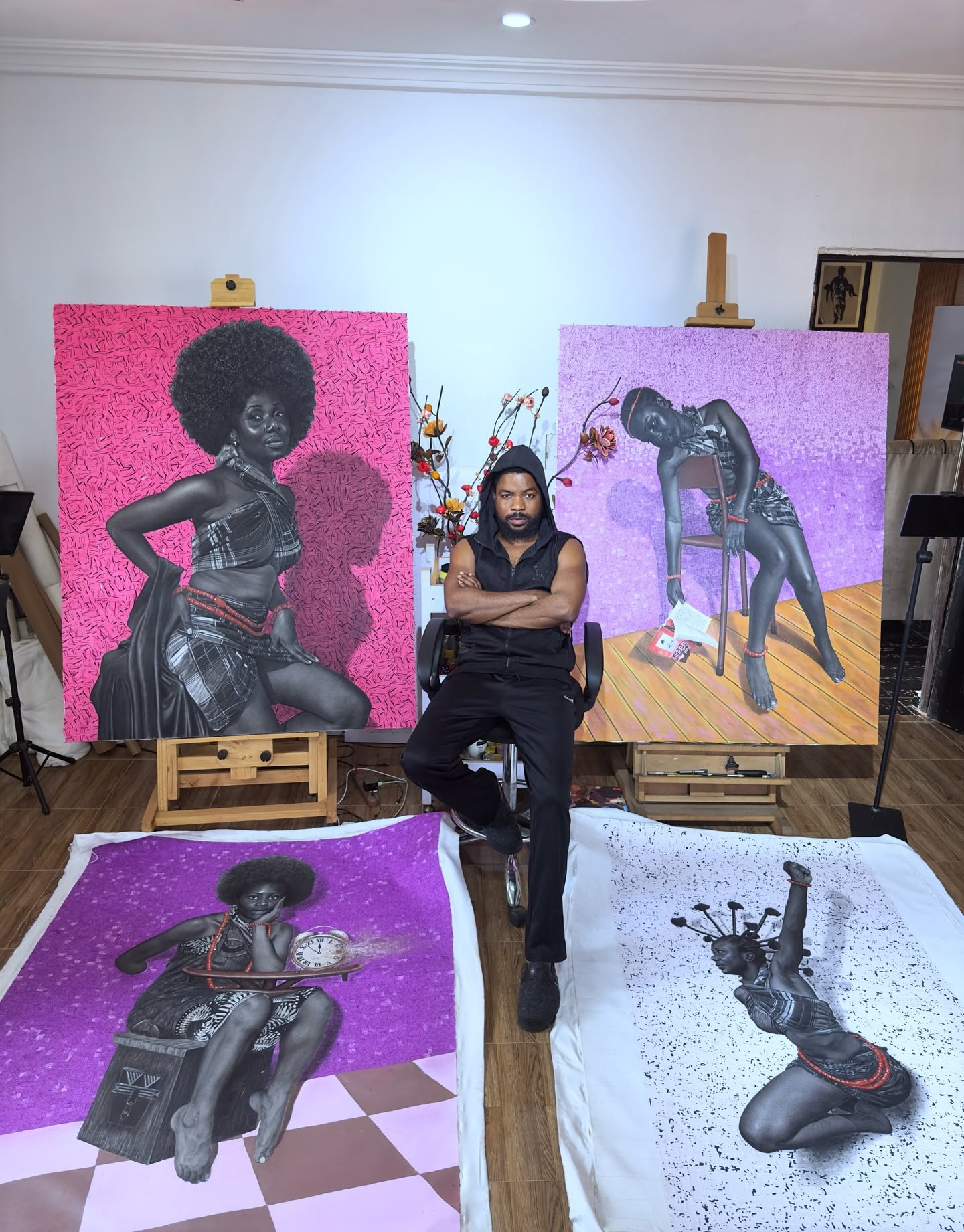 Hopex John assis au milieu de quatre grandes œuvres rose et violet