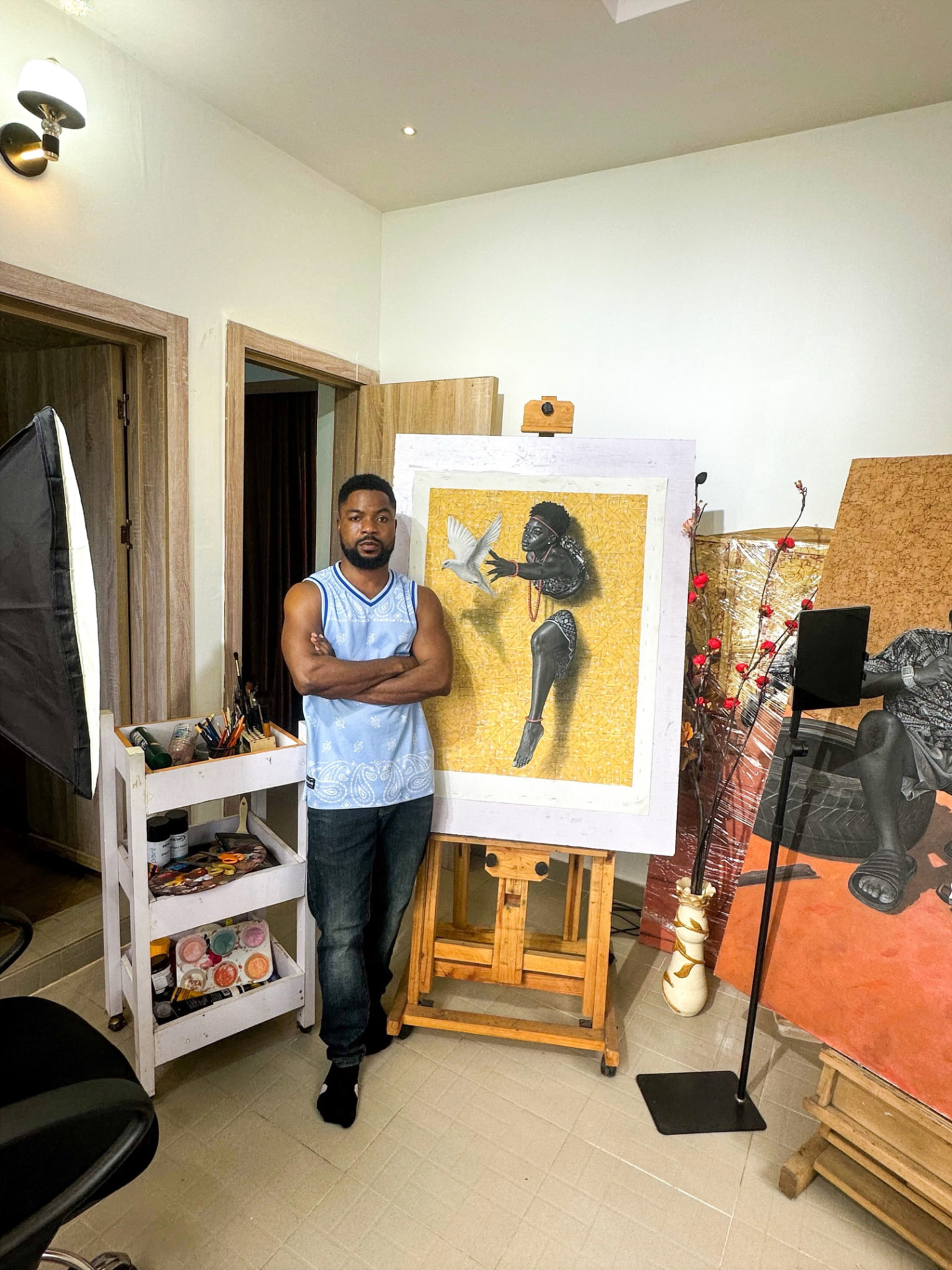 Hopex John dans son atelier à côté d'une de ses œuvres