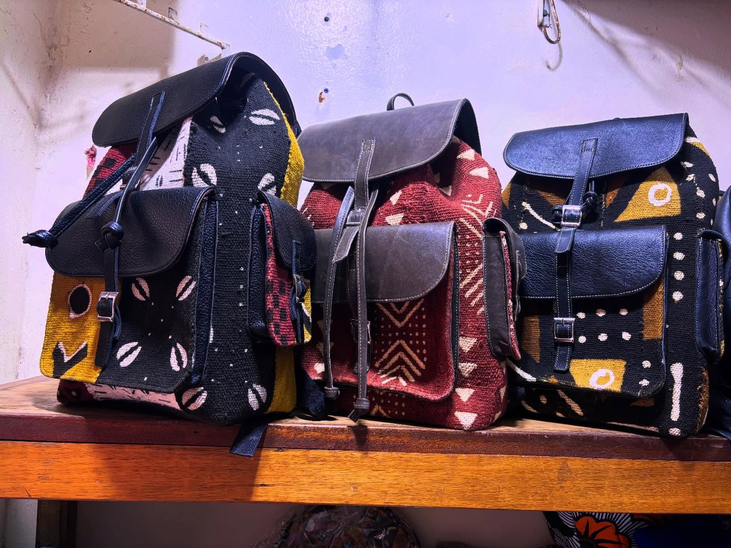 Trois sacs à dos en tissu bogolan et cuir sur une étagère