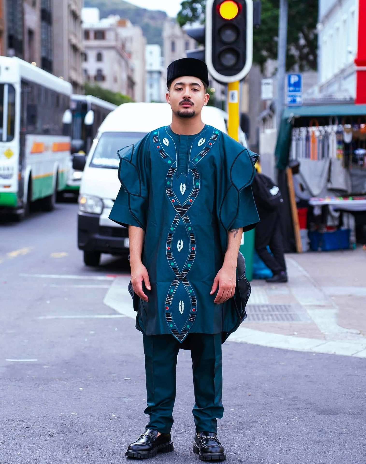 Agbada vert sapin brodé de médaillons noirs, verts et rouges, porté en ville