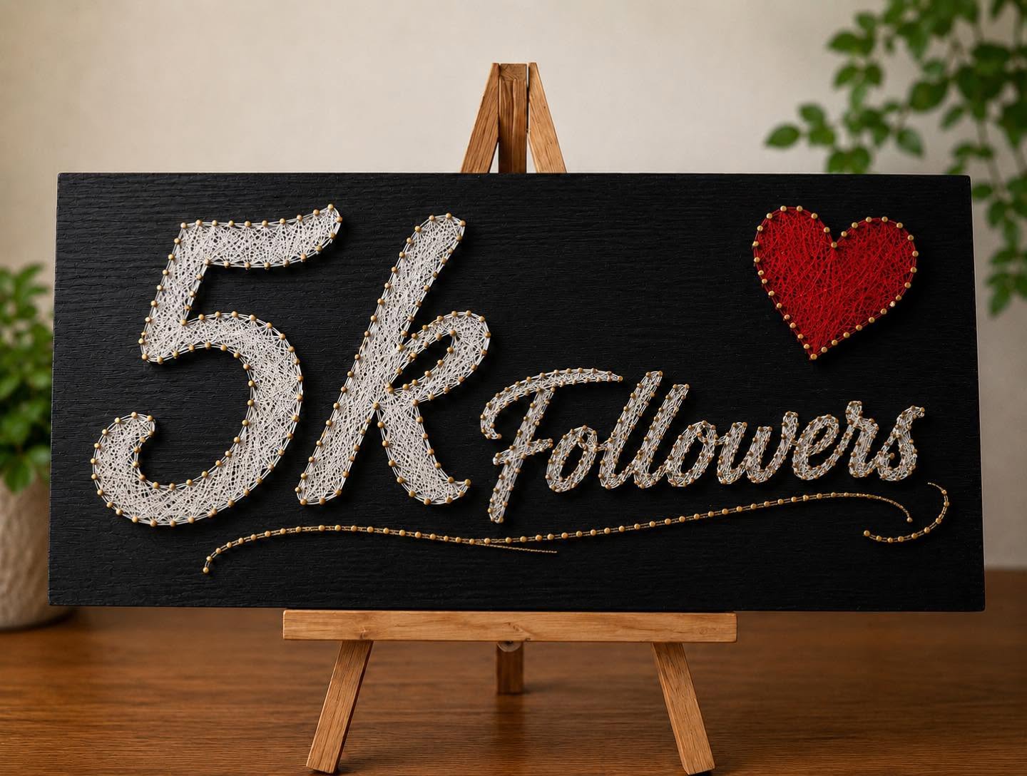 Tableau « 5k Followers » en fils blancs et cœur rouge sur panneau noir