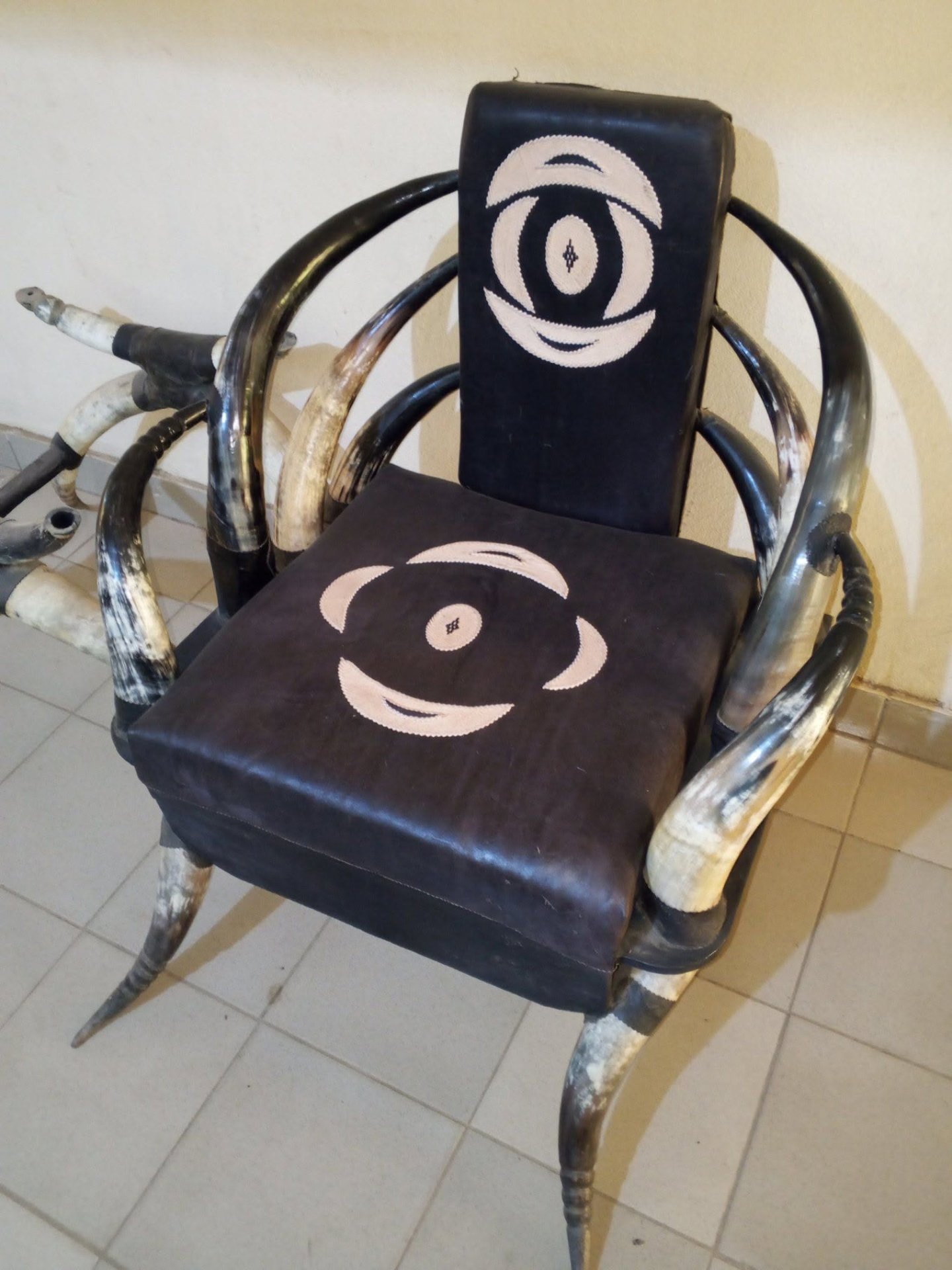 Fauteuil en cornes avec assise en cuir noir et motif appliqué beige
