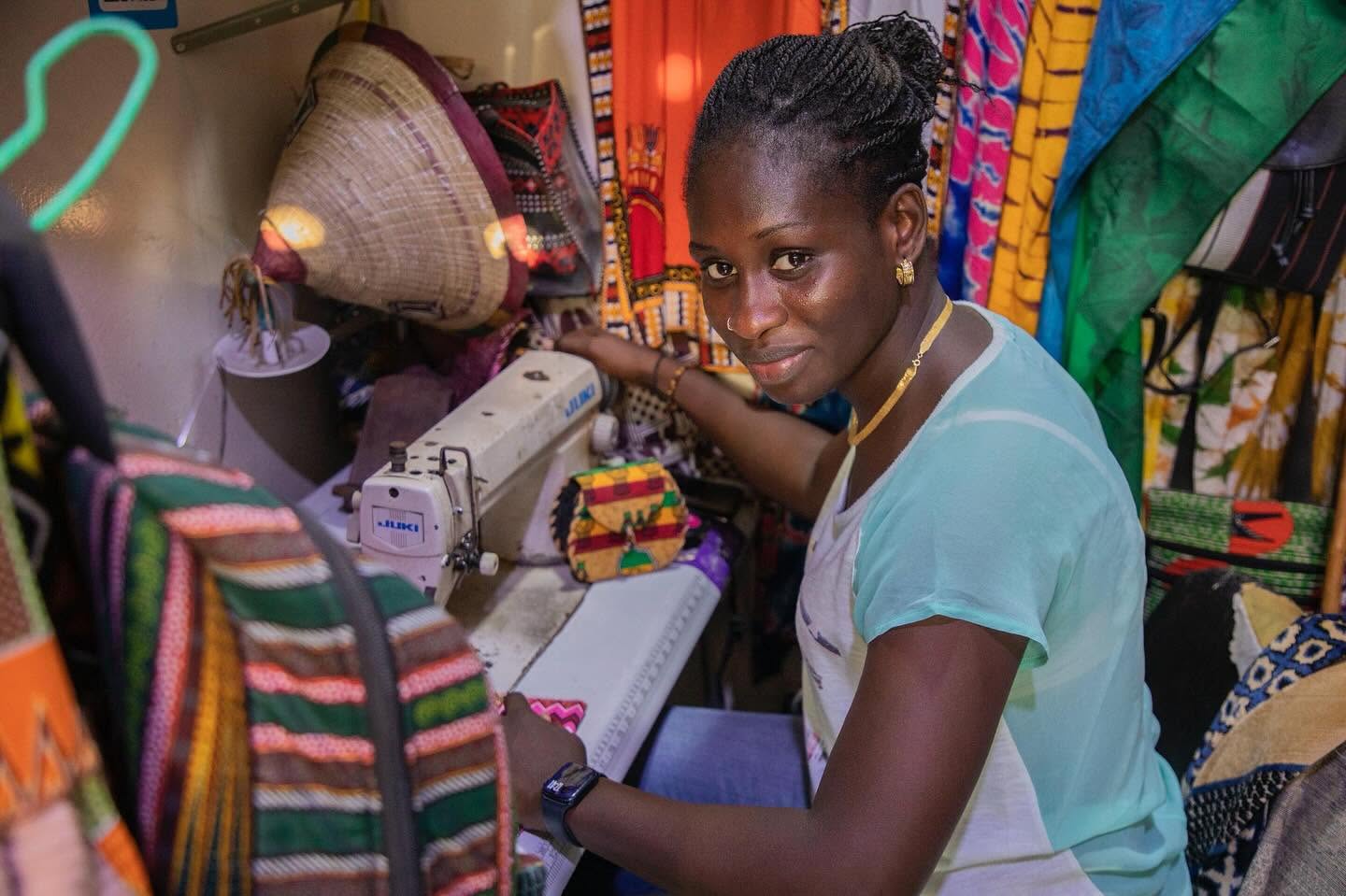 Couturière à sa machine dans l'atelier entouré de tissus colorés