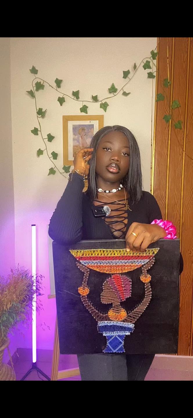 Jeune femme présentant un portrait africain coloré réalisé en fils tendus