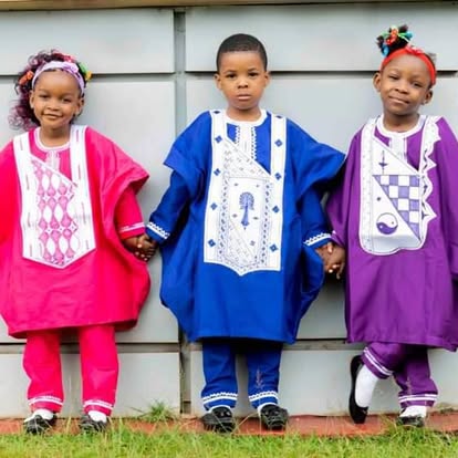 Trois enfants portant des agbadas brodés rose, bleu et violet