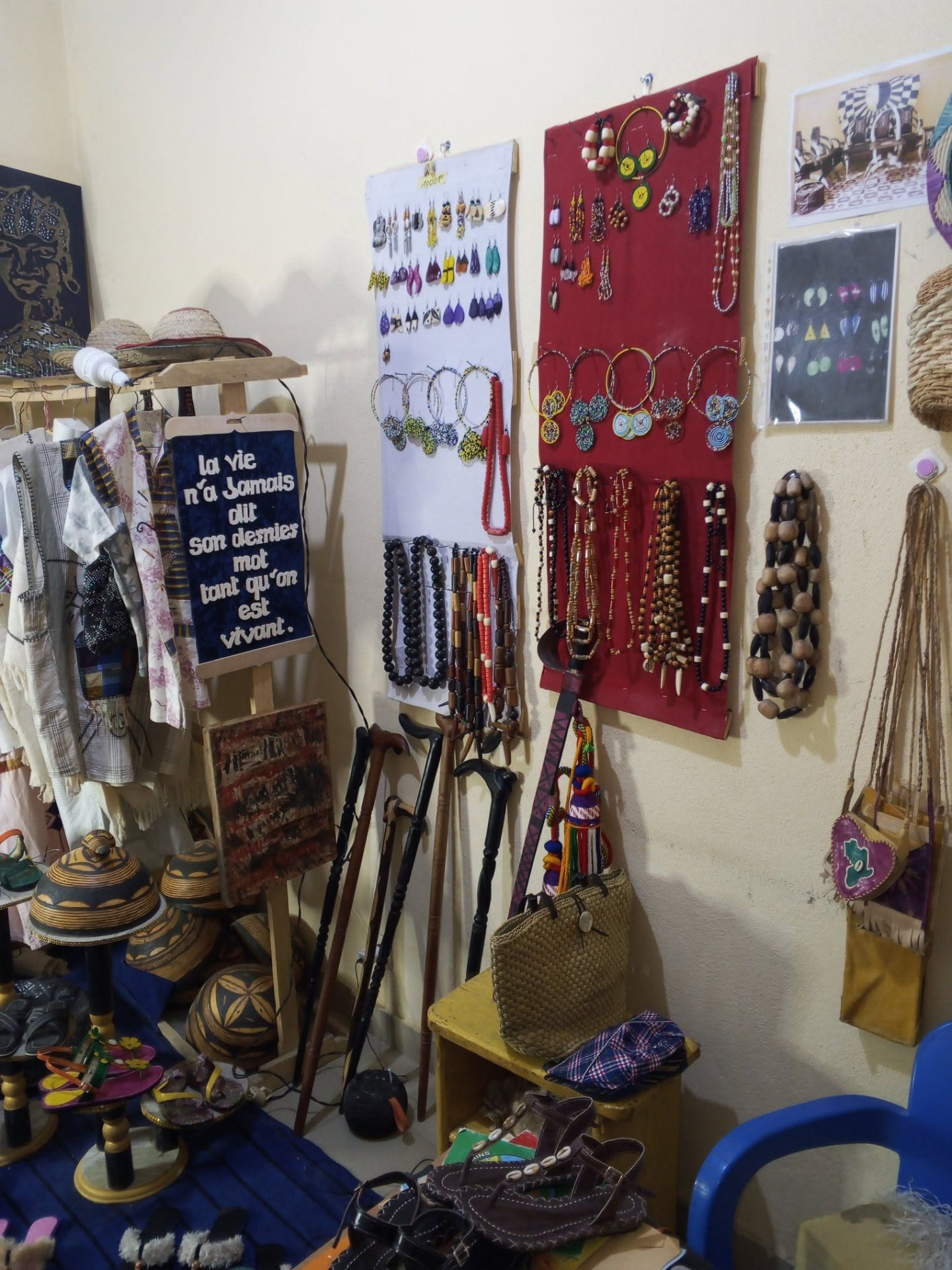 Mur d'exposition de bijoux, colliers, chapeaux, cannes et sacs à la boutique de Maroua