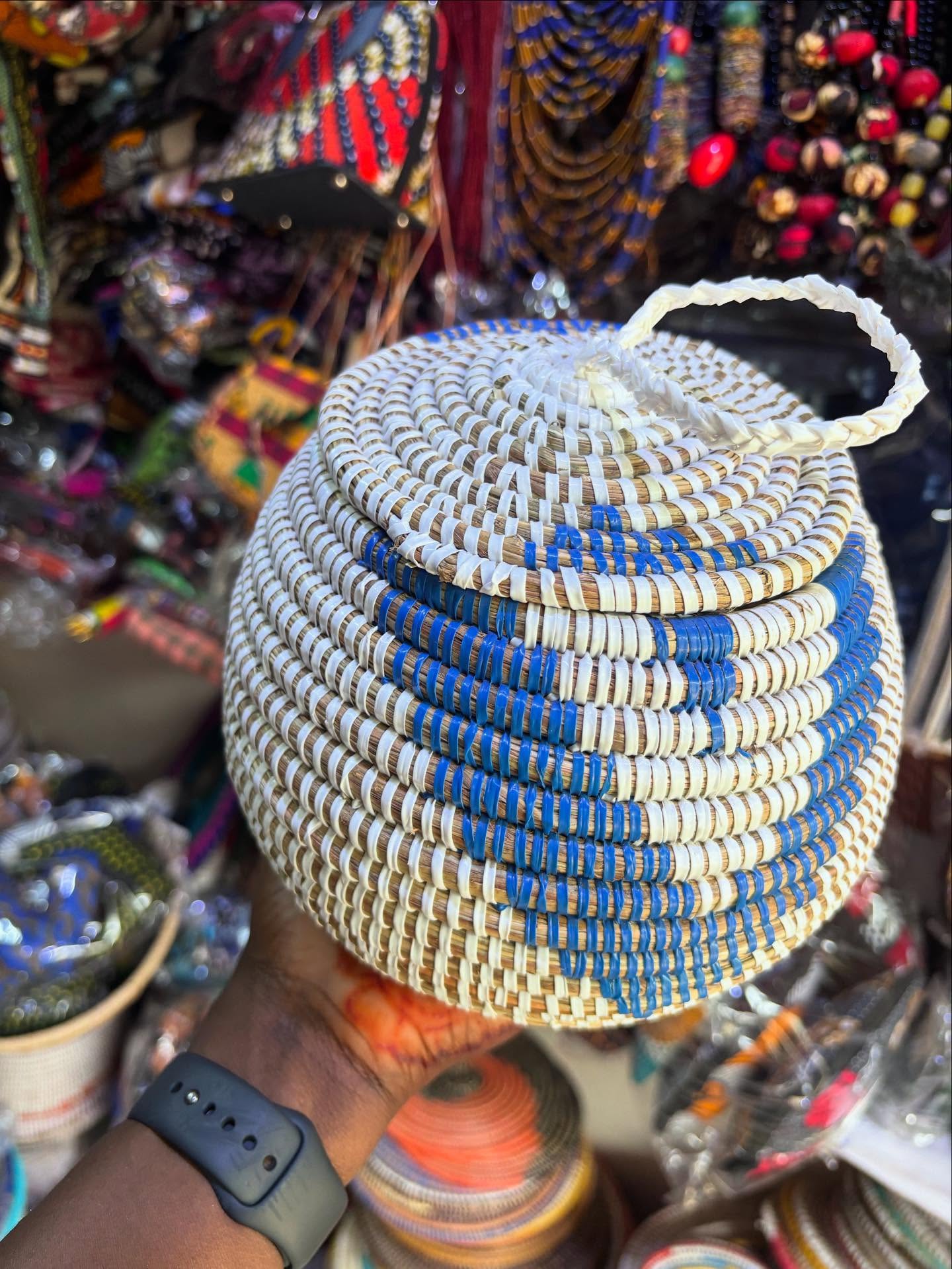 Panier tressé bleu et écru avec couvercle et anse, tenu en main