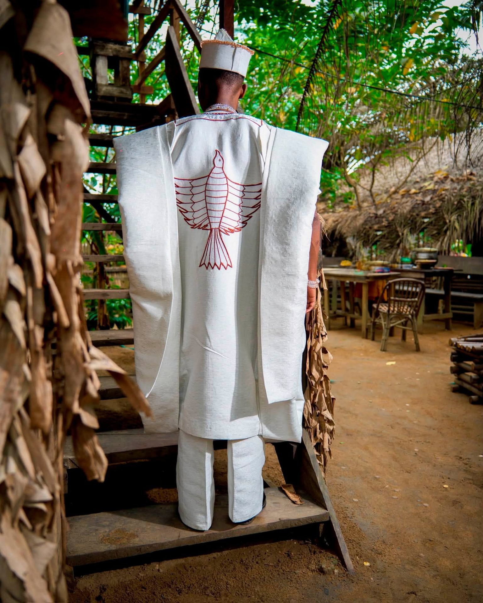 Dos d'un agbada blanc orné d'un grand oiseau brodé en fil bordeaux
