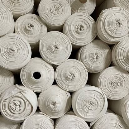 Rouleaux de tissu écru empilés dans l'atelier