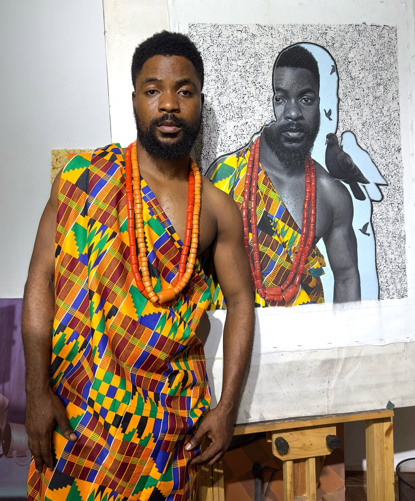 Hopex John en pagne kente devant son autoportrait avec colombe
