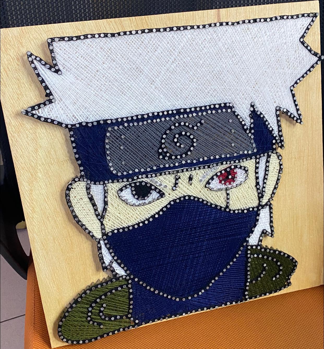 Portrait d'un personnage de manga au bandeau bleu réalisé en fils tendus sur bois clair