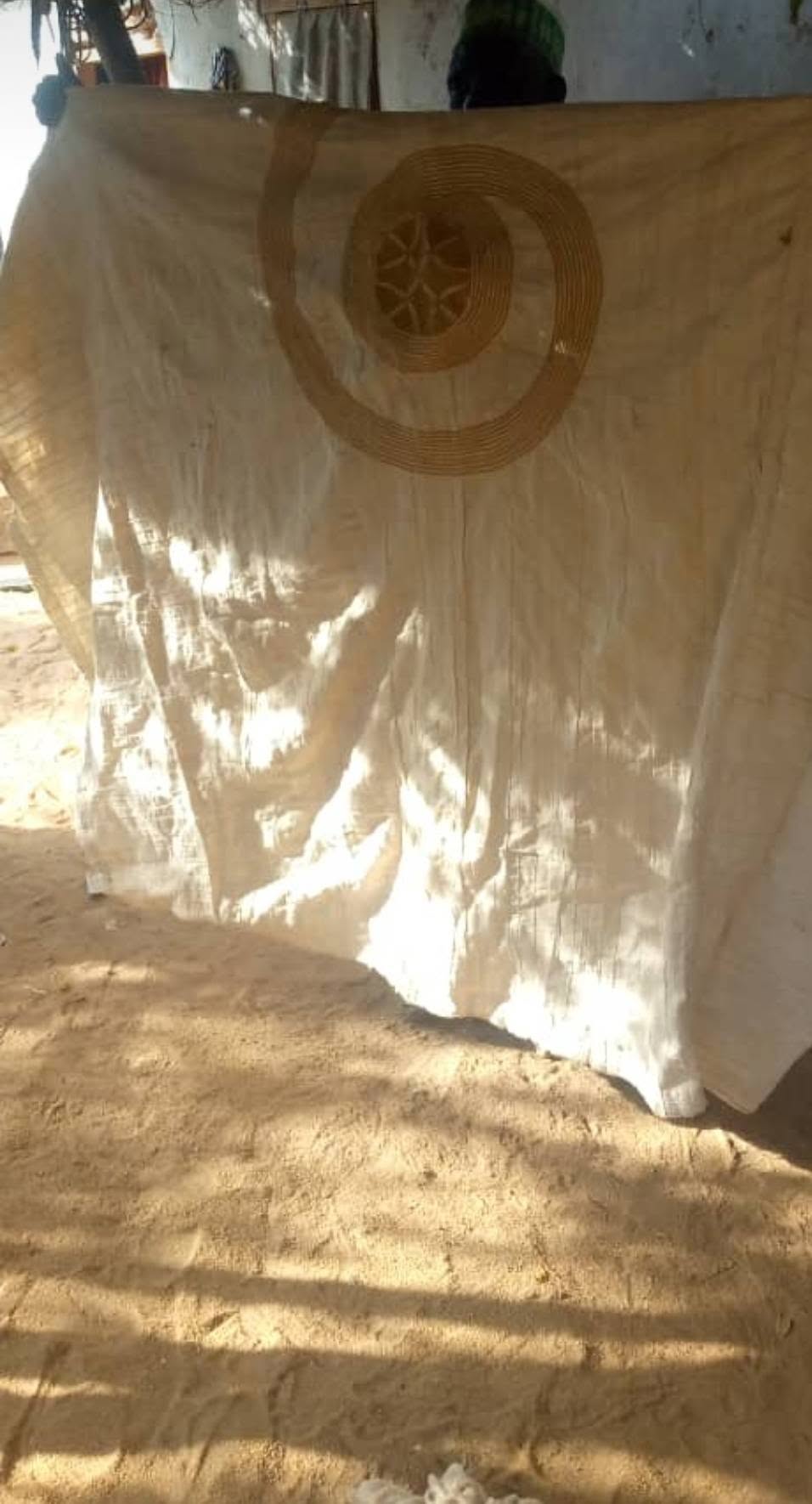 Grande étoffe artisanale claire ornée d'un motif circulaire traditionnel