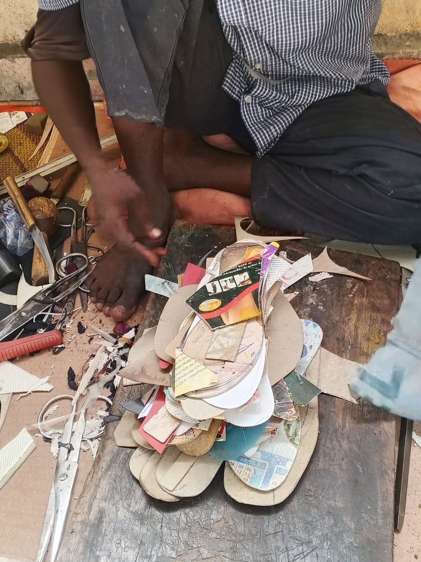Artisans découpant des semelles de tongs dans un atelier de cordonnerie