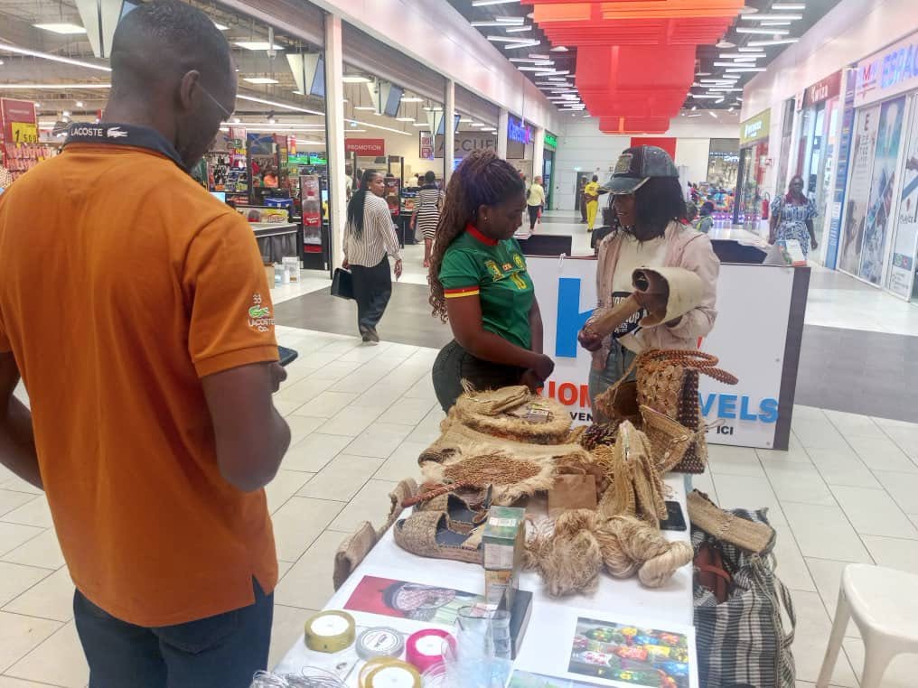 Stand EcoFibre dans une galerie commerciale avec sacs, sandales et pelotes de fibres