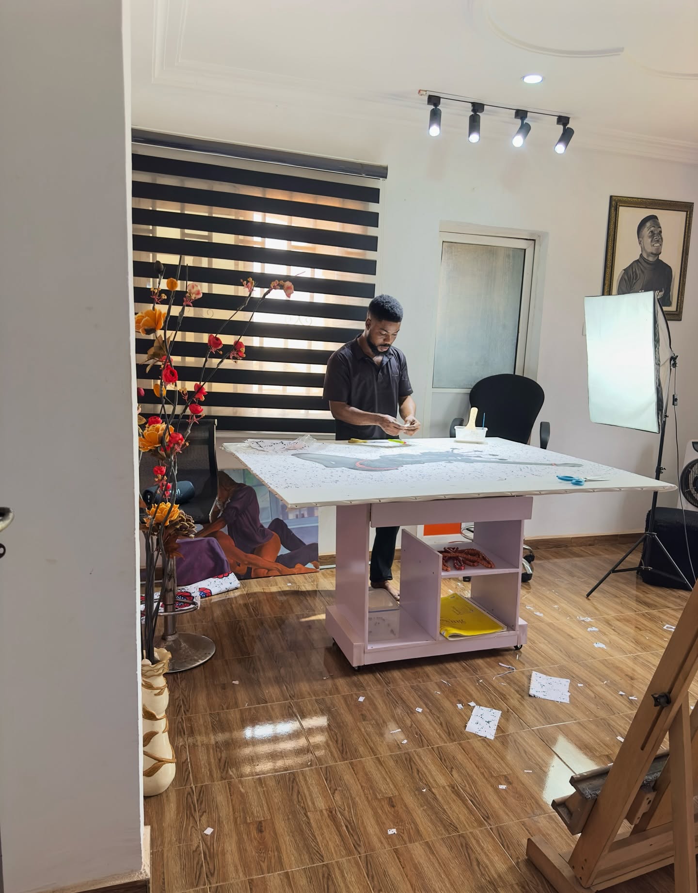 Hopex John travaillant une grande toile posée à plat sur une table