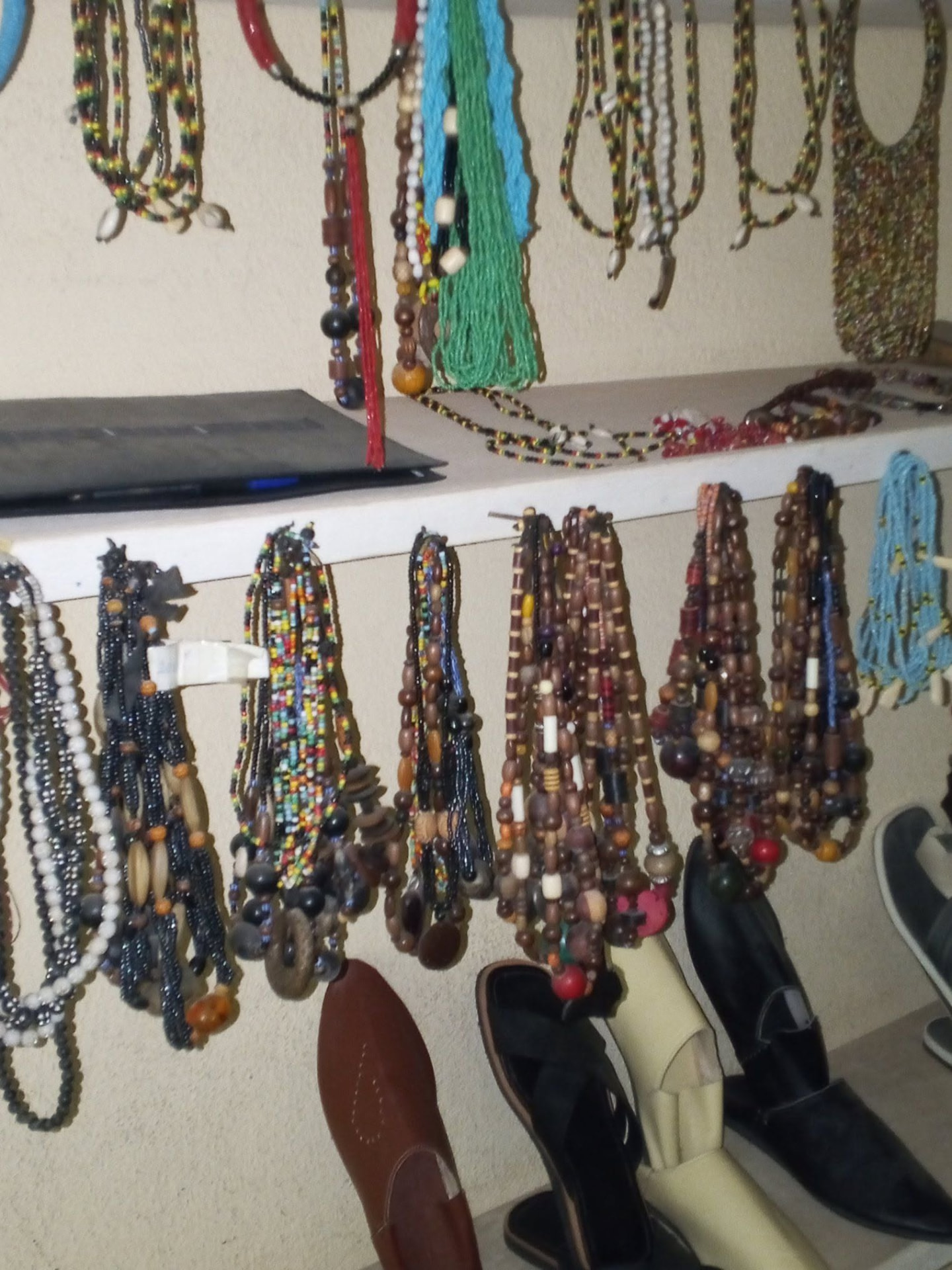 Colliers artisanaux en perles et graines suspendus au mur de la boutique