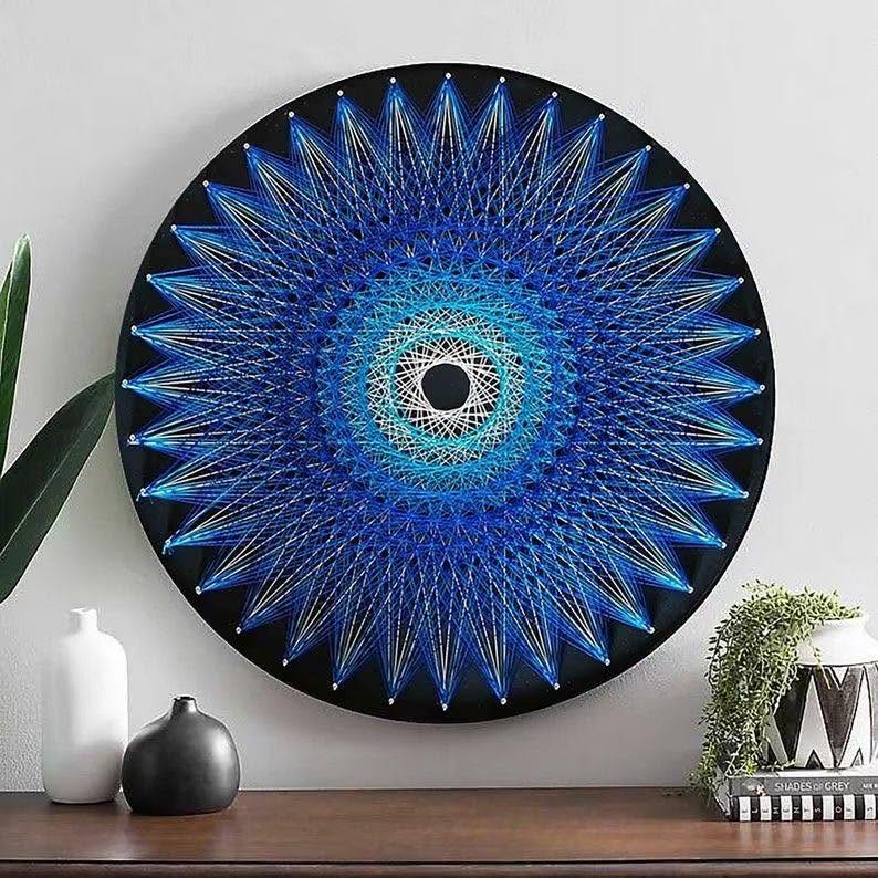 Grand mandala circulaire bleu réalisé en fils tendus sur fond noir