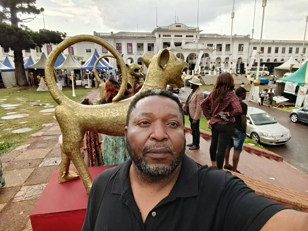 Portrait de Daouda Coulibaly devant les sculptures de léopards dorés au SIARC 2026