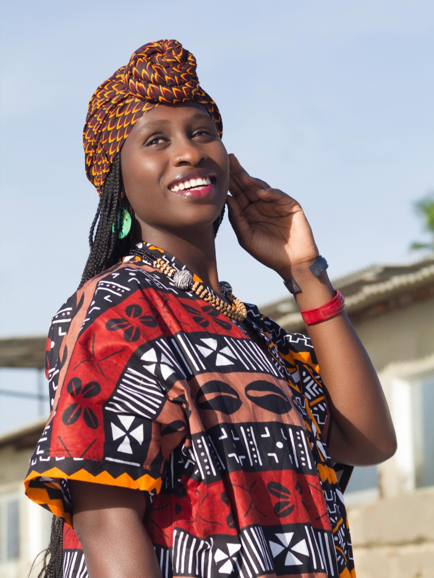 Femme souriante portant un foulard noué et une tunique aux motifs traditionnels